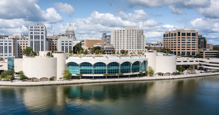 A photograph of the Monona Terrace and Convention center with the downtown Madison skyline.